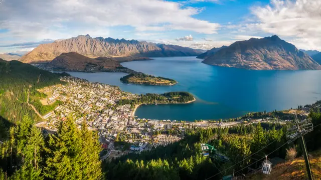 Queenstown seen from the Skyline gondola — the town on the shore of Lake Wakatipu with the Remarkables range beyond, a gondola cabin in the foreground.